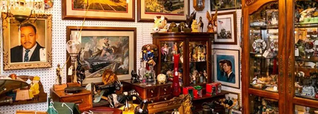 An antique shop displays vintage paintings, portraits, wooden furniture, figurines, and various collectibles.
